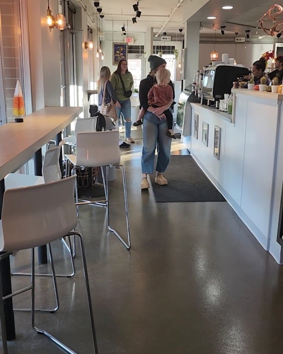 The long room: window bar on the left, the counter and espresso bar on the right, pendant lights overhead.