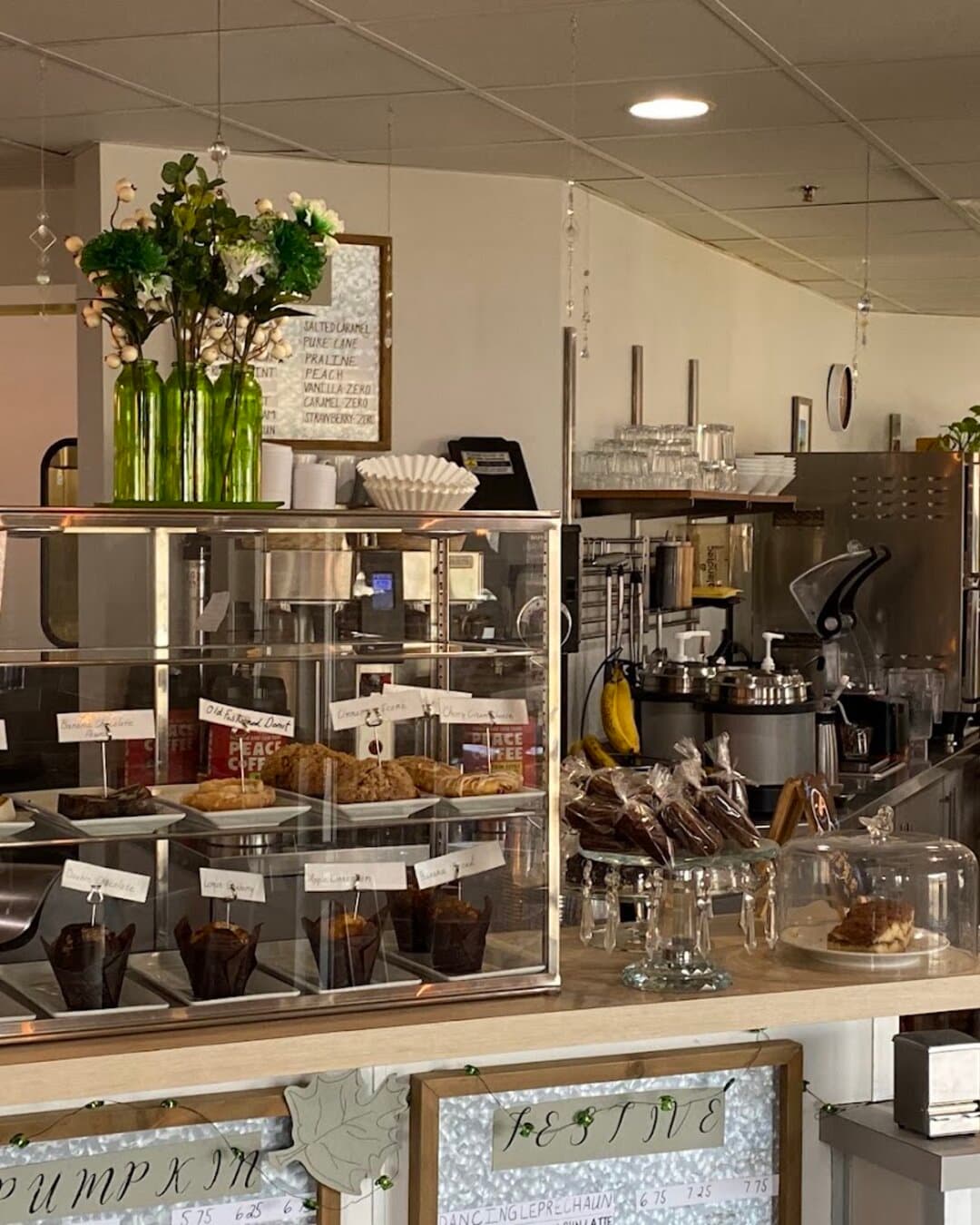 The espresso bar behind the counter, the pastry cabinet and fresh flowers.