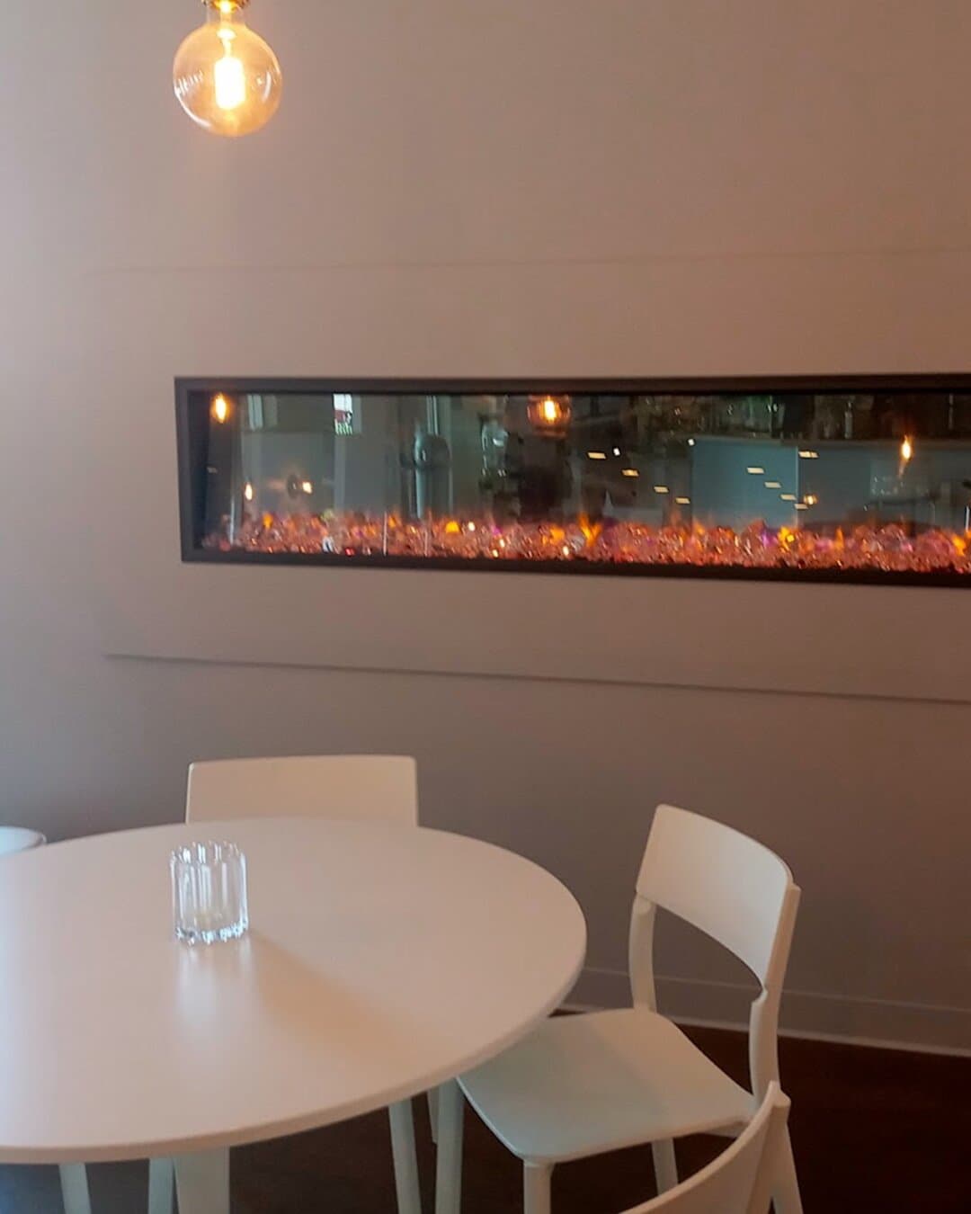 A round table for two in front of the long fireplace.