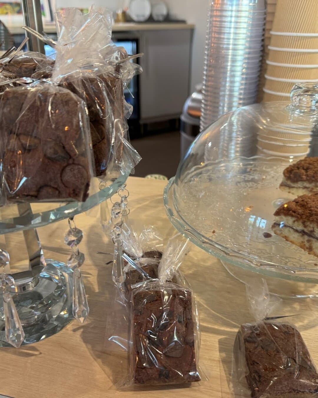 Brownies bagged for the road and cake under a glass dome at the counter.