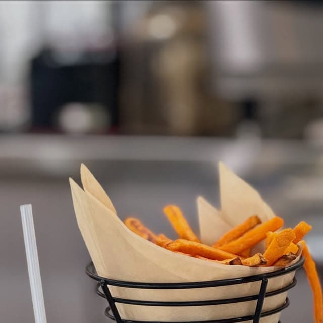 Sweet potato fries in a paper-lined wire basket.